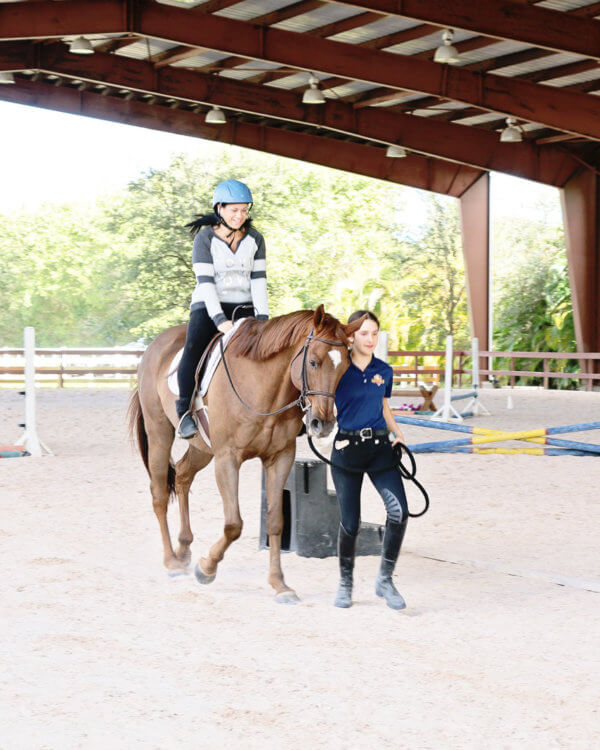 Trainer giving lady riding lessons