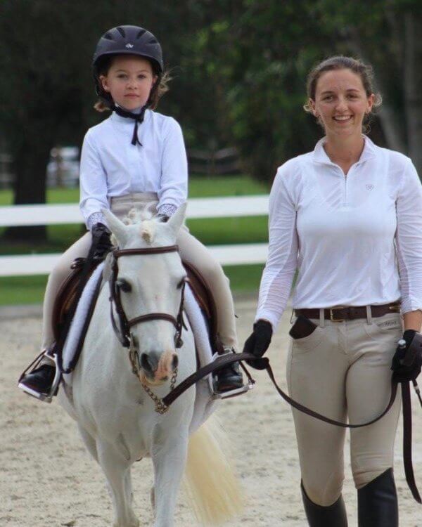 Trainer giving child horse riding lessons